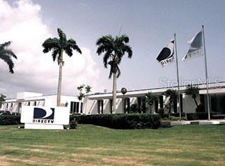 A low-rise commercial building with a DirecTV sign, palm trees, and two flags outside — 848 PR-848 INT. PR-887, CAROLINA, PR