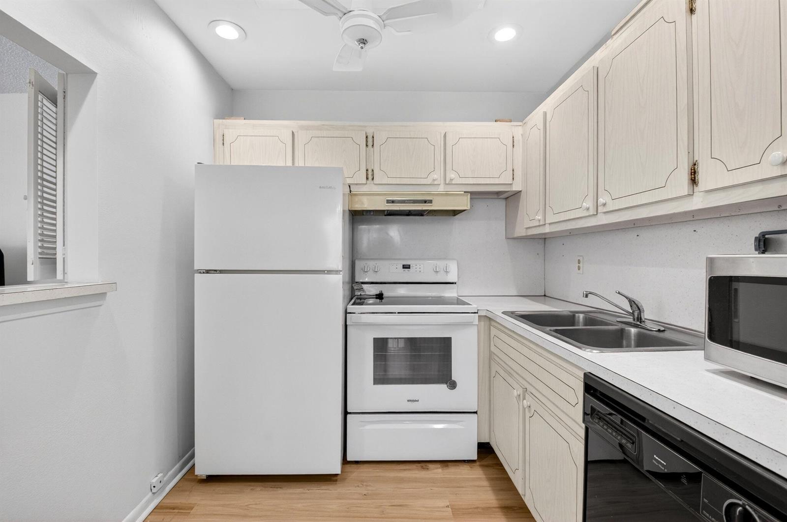 A kitchen features white appliances, light wood-grain cabinets, and a double-basin stainless steel sink — 480 Boynton Beach Boulevard # 204, Boynton Beach FL 33435, BOYNTON BEACH, FL