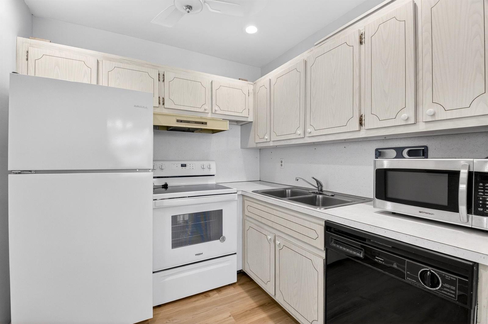 A kitchen features white appliances, light wood-toned cabinets, a double sink, and light-colored countertops — 480 Boynton Beach Boulevard # 204, Boynton Beach FL 33435, BOYNTON BEACH, FL