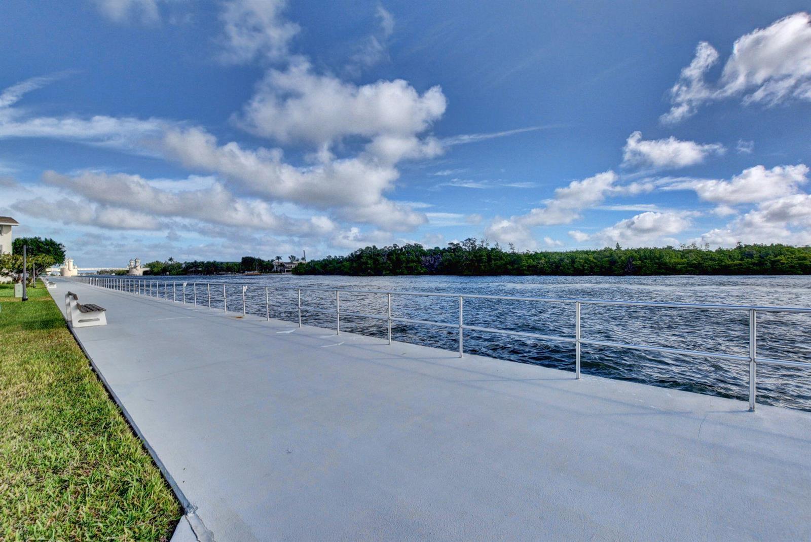 A paved walkway with a metal railing runs alongside a river under a cloudy sky — 480 Boynton Beach Boulevard # 204, Boynton Beach FL 33435, BOYNTON BEACH, FL