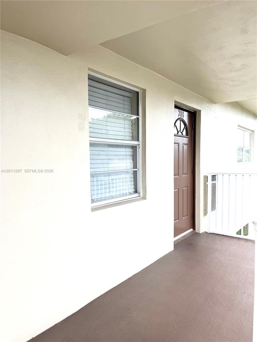 An exterior view shows a brown door numbered 208 next to a window and railing — 551 NW 80th Ter # 208, Margate FL 33063, MARGATE, FL