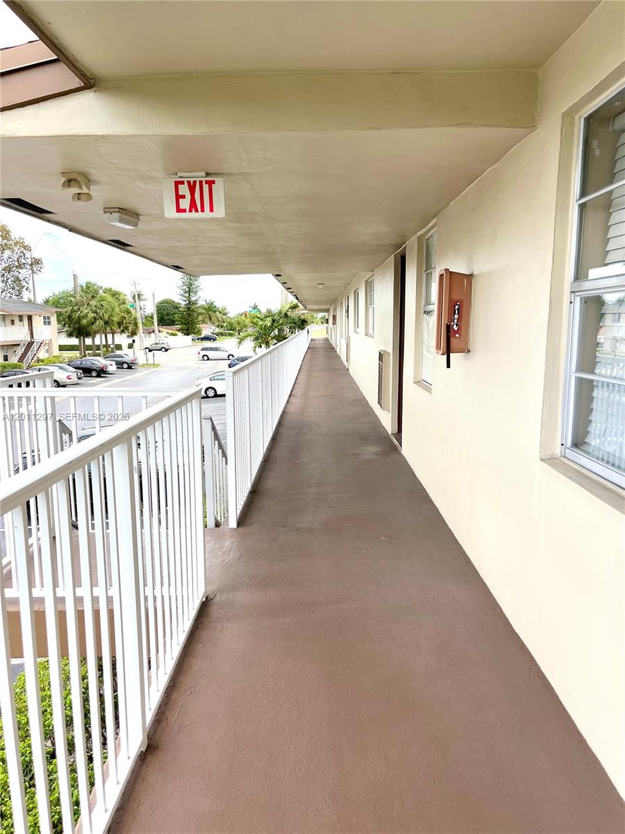 An outdoor walkway with a white railing overlooks a parking lot — 551 NW 80th Ter # 208, Margate FL 33063, MARGATE, FL