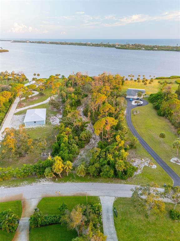 An aerial view shows a vacant, wooded lot situated between two houses near a large body of water — BAYSHORE DRIVE, ENGLEWOOD, FL