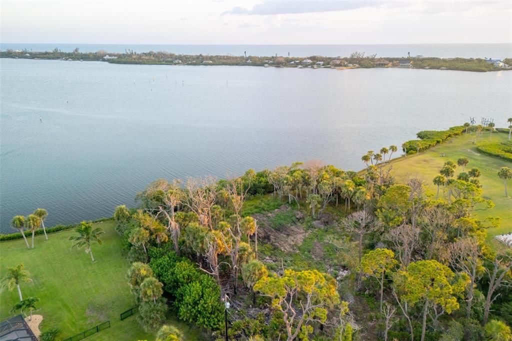 An aerial view shows a waterfront lot with trees and vegetation bordering a large bay — BAYSHORE DRIVE, ENGLEWOOD, FL