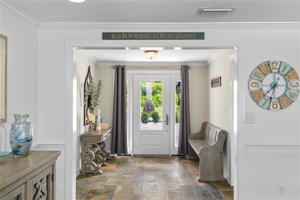 An entryway features a stone floor, a wooden bench, a console table, and a front door — 232 QUAY ASSISI, NEW SMYRNA BEACH, FL