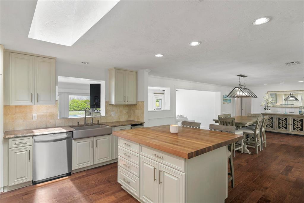 A kitchen features a wooden island, stainless steel appliances, and light cabinetry with tile backsplash — 232 QUAY ASSISI, NEW SMYRNA BEACH, FL