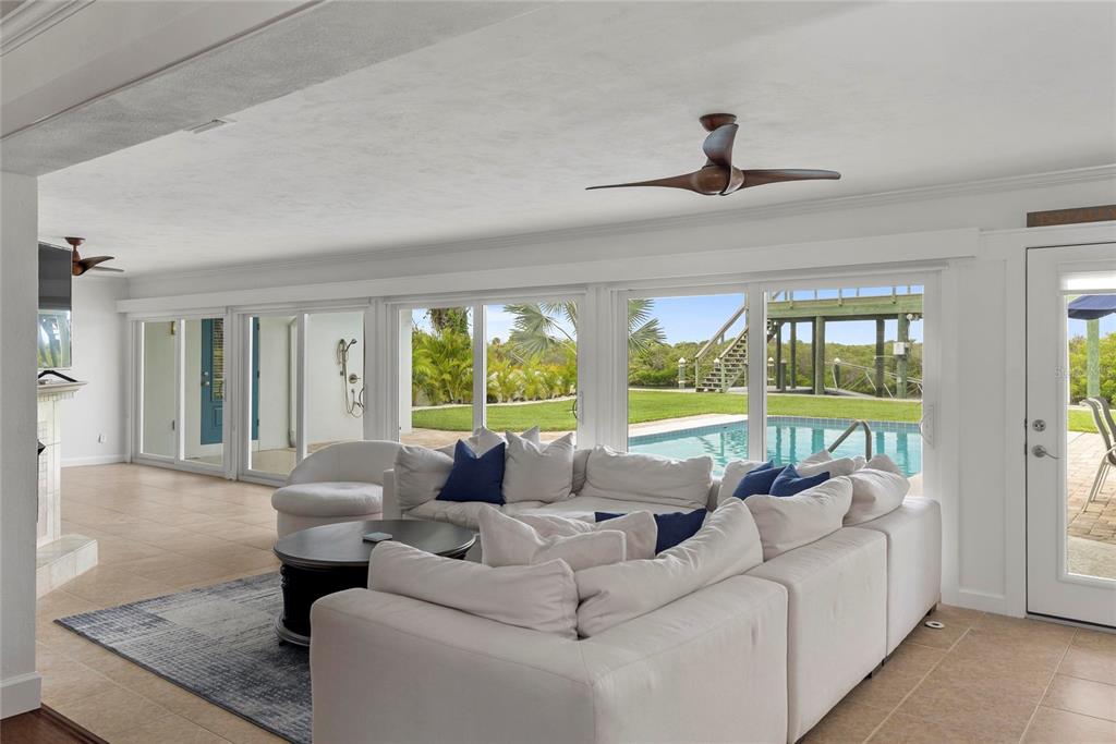 A living room with a white sectional sofa faces a pool and outdoor deck area — 232 QUAY ASSISI, NEW SMYRNA BEACH, FL