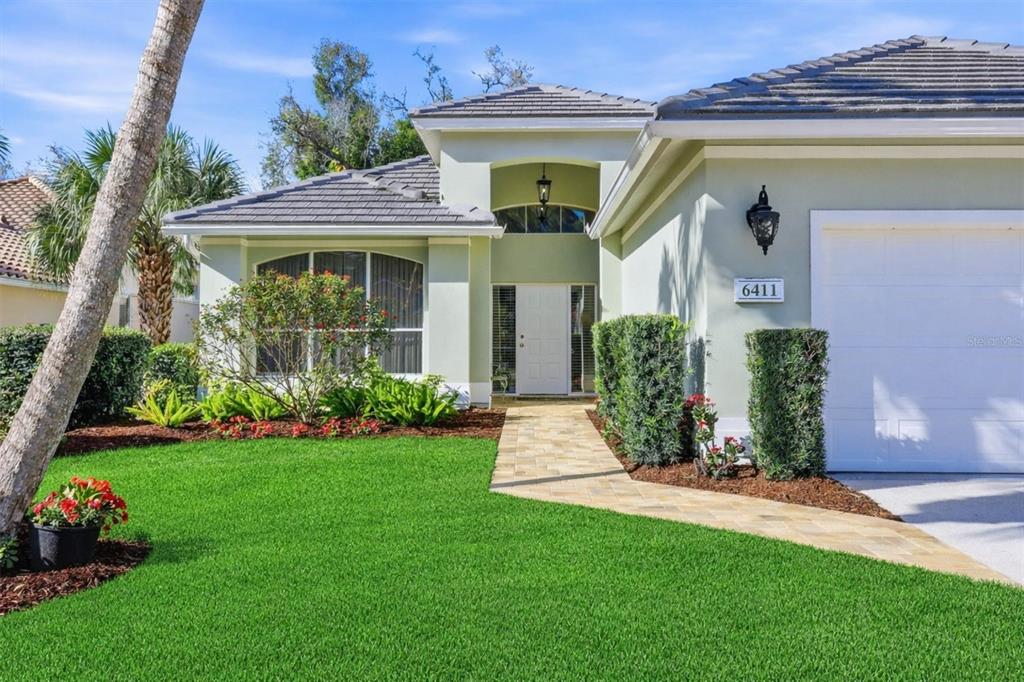 A single-story house with a gray tile roof, white garage, and palm trees in front — 6411 BERKSHIRE PLACE, UNIVERSITY PARK, FL