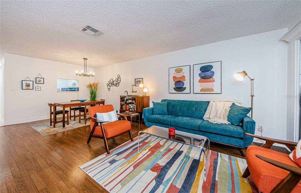 A living and dining room with a teal sofa, orange chairs, and hardwood floors — 601 N HERCULES AVENUE UNIT 508, CLEARWATER, FL