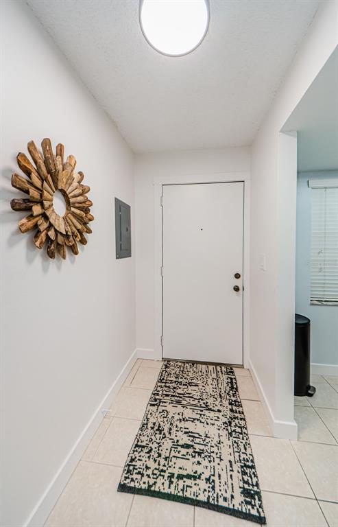 A white entryway features a wooden sunburst wall mirror, a patterned rug, and tile flooring — 601 N HERCULES AVENUE UNIT 508, CLEARWATER, FL