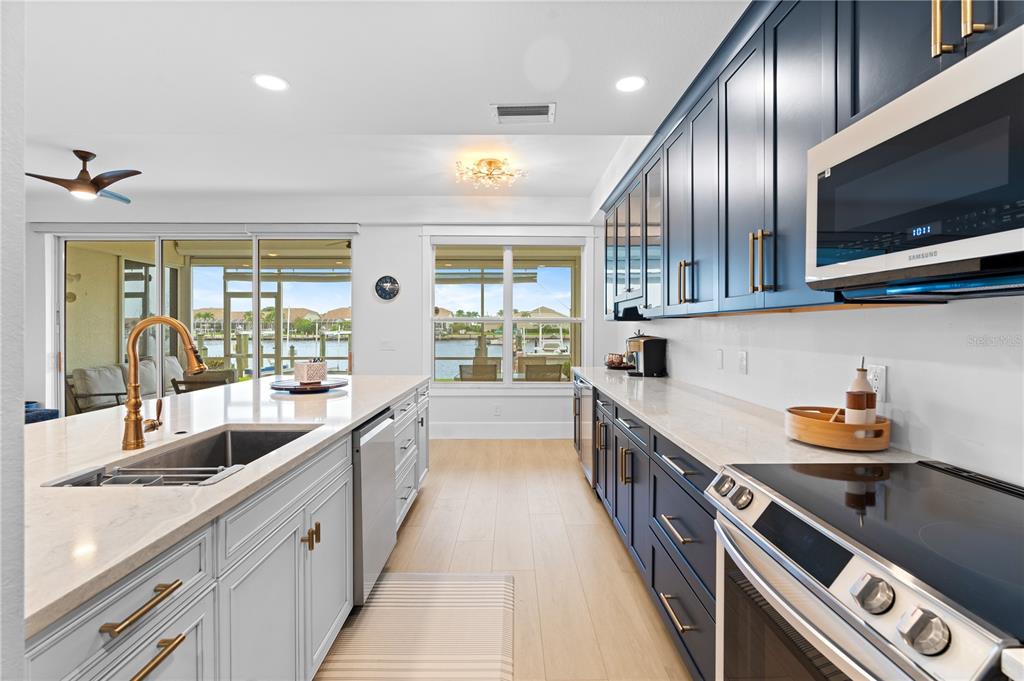 A kitchen features dark blue cabinets, a white island with a sink, and waterfront views — 380 STELLA MARIS DRIVE N UNIT 2602, NAPLES, FL