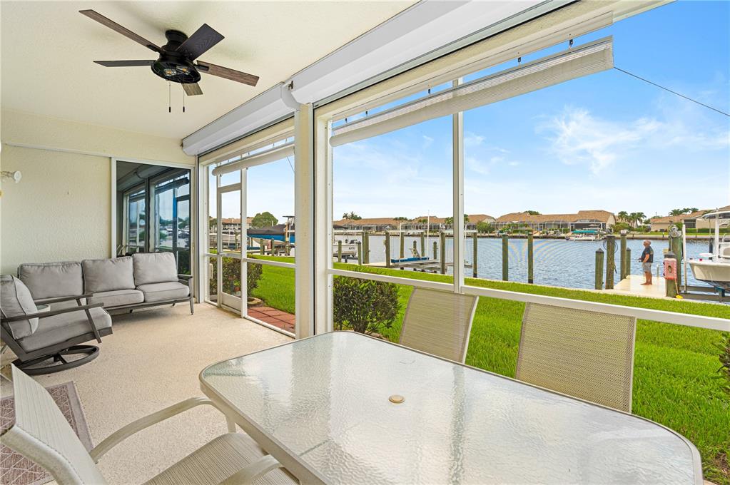 A screened-in patio features outdoor furniture and a view of a canal with boats — 380 STELLA MARIS DRIVE N UNIT 2602, NAPLES, FL