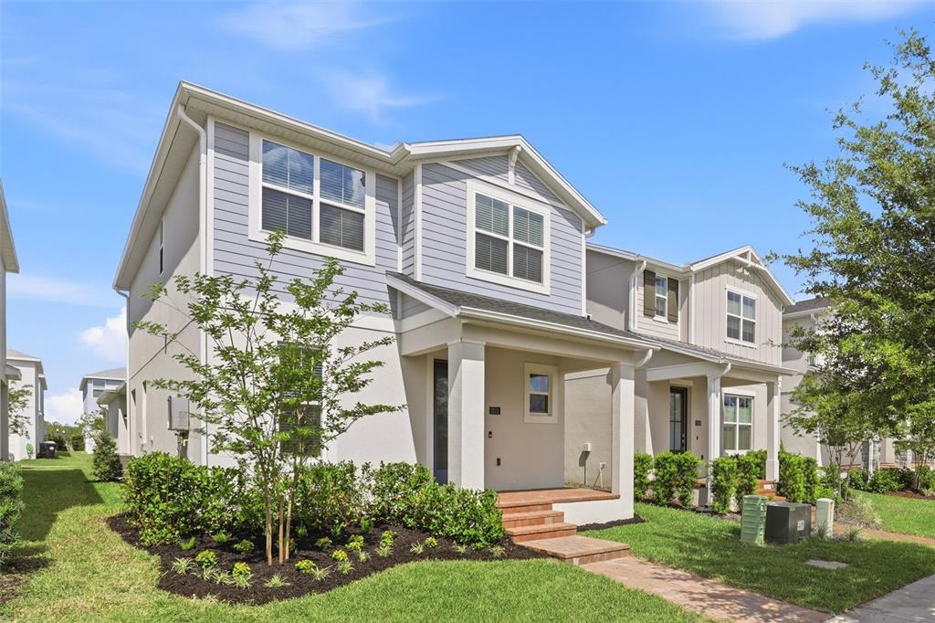 A two-story townhouse with light blue siding, a covered front porch, and a landscaped yard — 2512 CEDAR ROSE STREET, APOPKA, FL