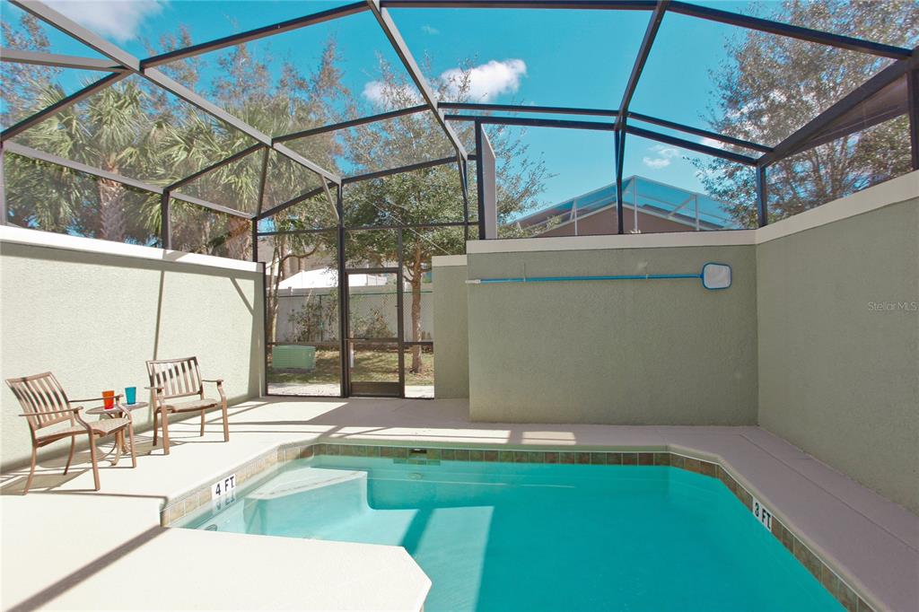 A screened-in patio features a small swimming pool with light-colored concrete decking and walls — 2931 BANANA PALM DRIVE, KISSIMMEE, FL