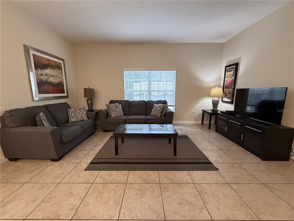 A living room features gray sofas, a coffee table, a television, and tile flooring — 2931 BANANA PALM DRIVE, KISSIMMEE, FL