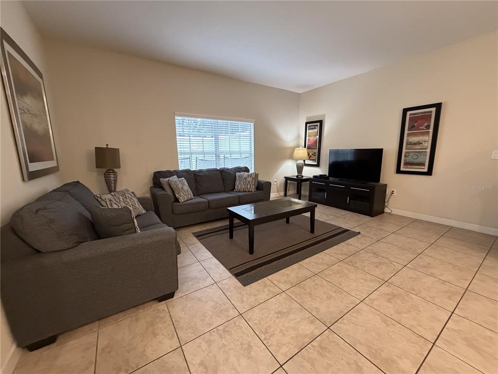 A living room features gray sofas, a coffee table, a television, and tile flooring — 2931 BANANA PALM DRIVE, KISSIMMEE, FL