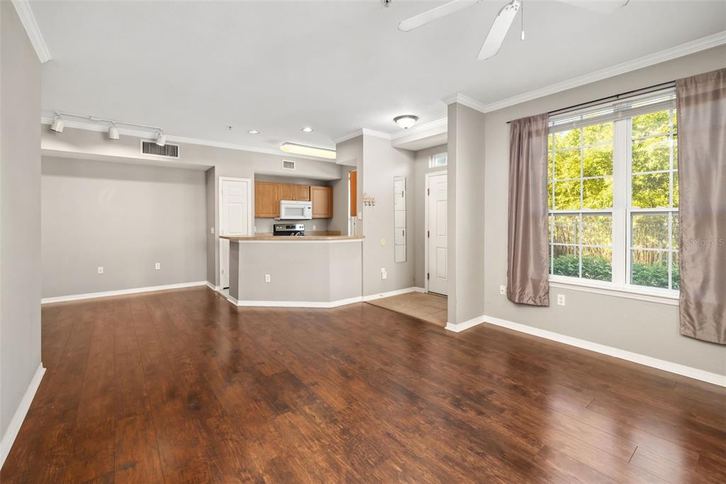 An open-concept living area with wood-look flooring, a kitchen breakfast bar, and a large window — 5501 ROSEHILL ROAD UNIT 103, SARASOTA, FL
