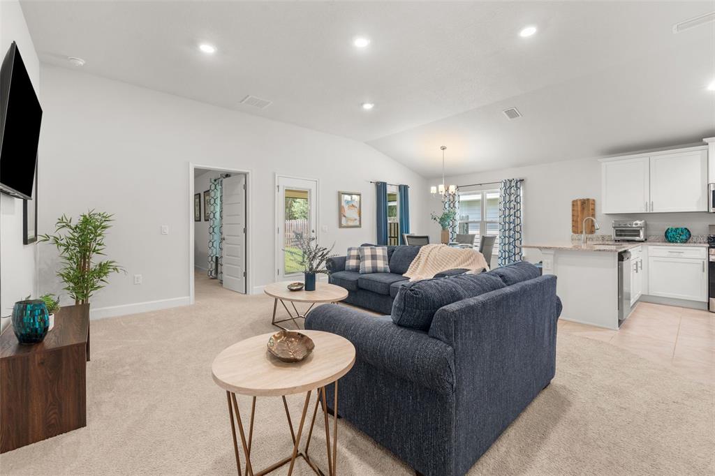 A living room with a blue sofa, two round tables, and an open-concept kitchen — 12692 NW 162ND DRIVE, ALACHUA, FL