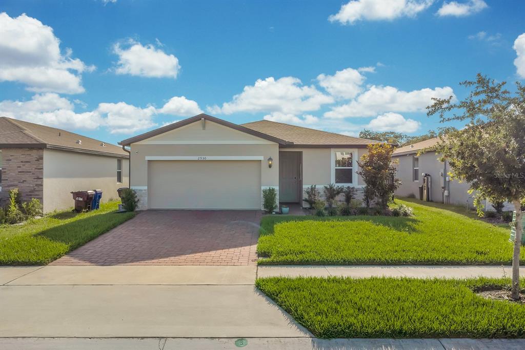 A single-story suburban house with a beige exterior, a two-car garage, and a paved driveway — 2950 SUNSTAR DRIVE, ST CLOUD, FL