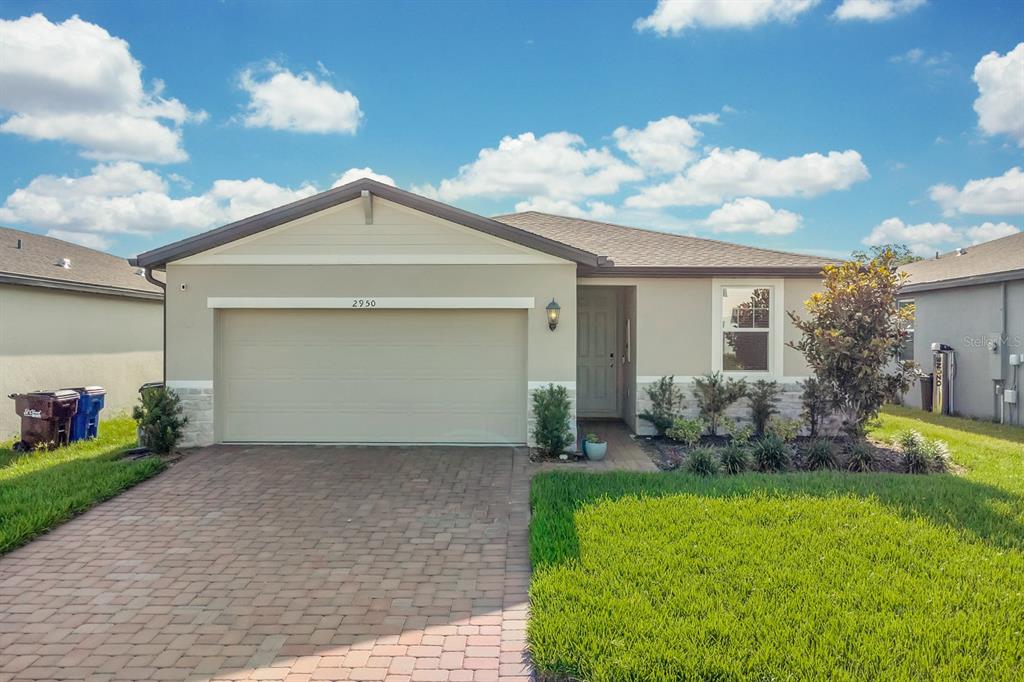 A single-story house with a beige stucco exterior, stone accents, and a paved driveway — 2950 SUNSTAR DRIVE, ST CLOUD, FL
