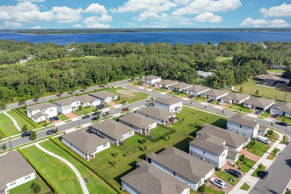 An aerial view shows a suburban neighborhood of single-family homes near a large lake — 2950 SUNSTAR DRIVE, ST CLOUD, FL