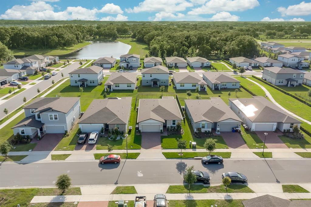 An aerial view shows a suburban neighborhood with single-family homes, paved streets, and a pond — 2950 SUNSTAR DRIVE, ST CLOUD, FL