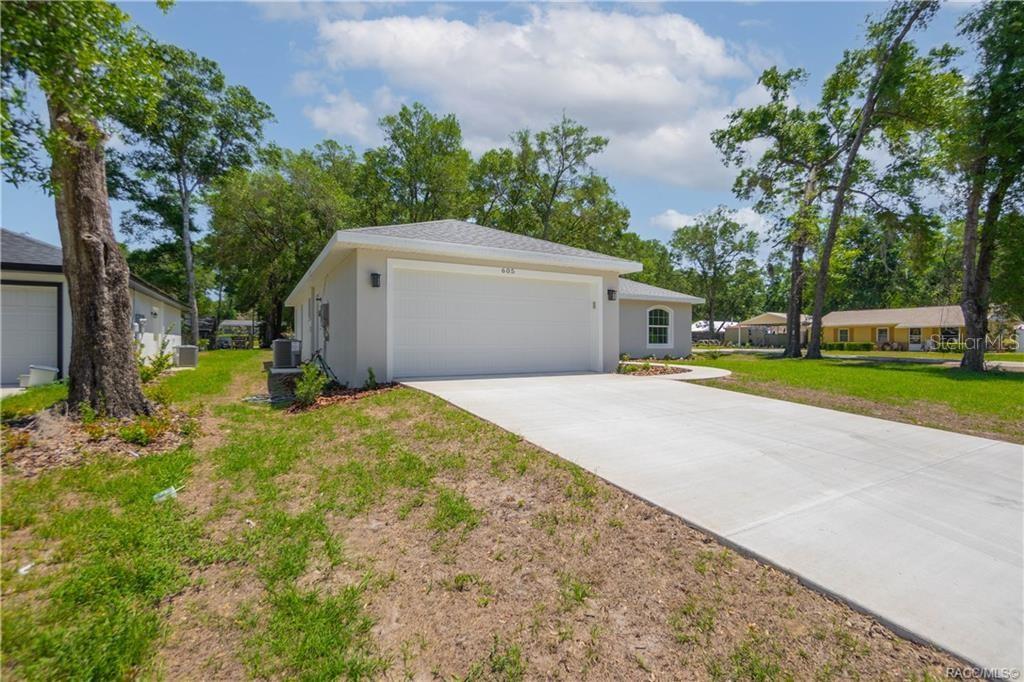 A light-colored house with a two-car garage and a concrete driveway sits on a lot — 605 N CORBIN AVENUE, INVERNESS, FL