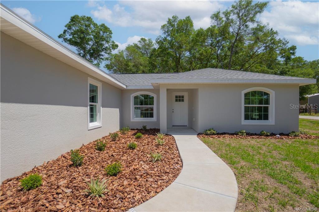 A light-colored house exterior features a concrete walkway leading to a white front door — 605 N CORBIN AVENUE, INVERNESS, FL