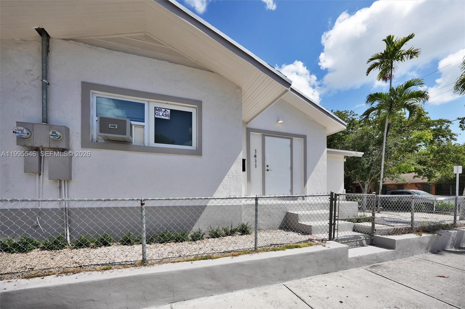 A white house exterior features a chain-link fence, a window air conditioner, and concrete steps — 1411 SW 3rd st # 2, Miami FL 33135, MIAMI, FL