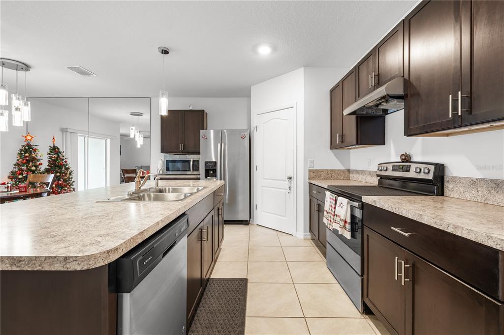 A kitchen features dark wood cabinets, a large island with a sink, and stainless appliances — 415 FRANCISCO WAY, KISSIMMEE, FL