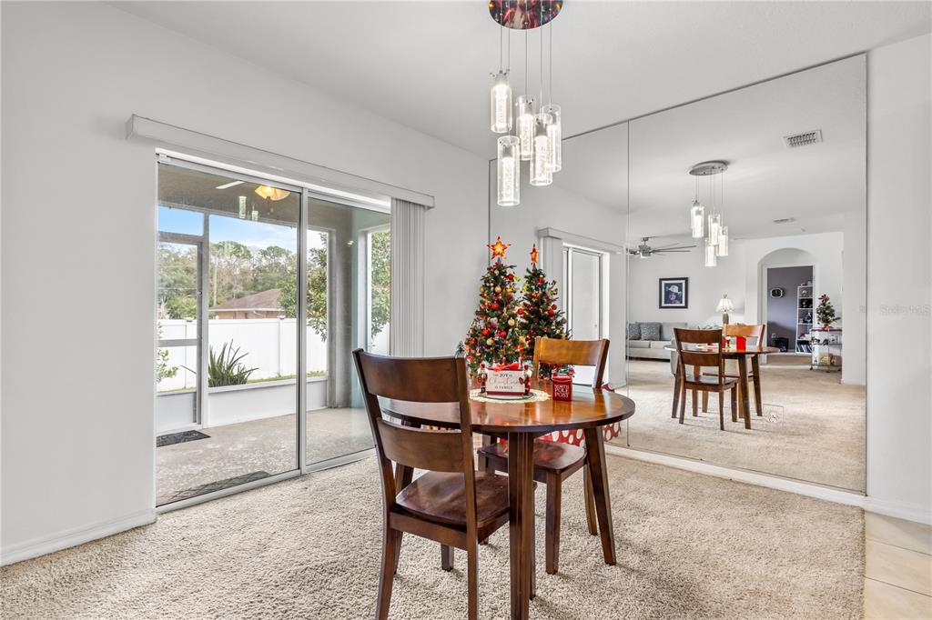 A dining area features a round wooden table, a mirrored wall, and a sliding glass door — 415 FRANCISCO WAY, KISSIMMEE, FL