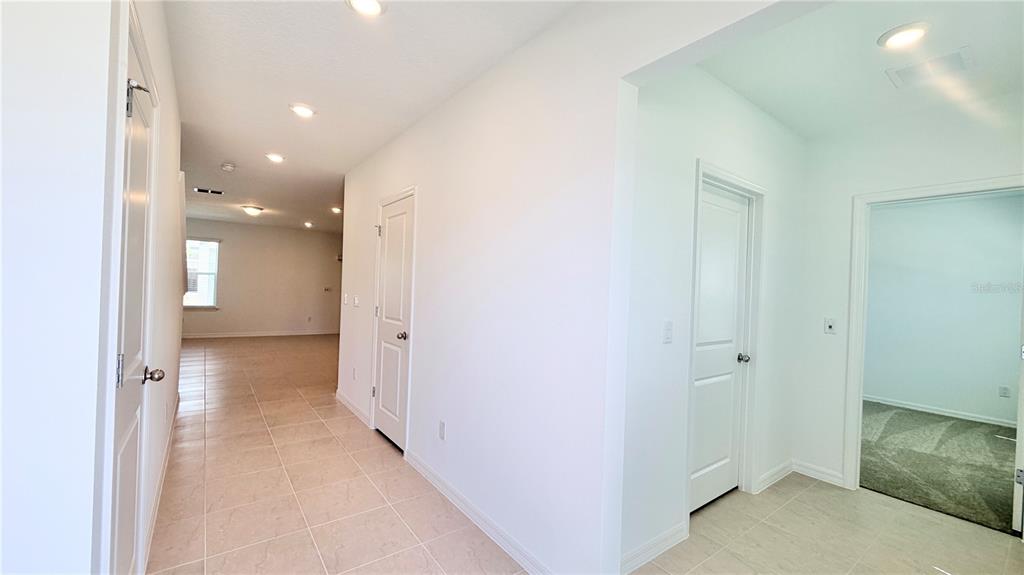 A bright hallway with tiled floors leads to an open living area and two doors — 5694 ENCHANTED MEADOW ALLEY UNIT A, CLERMONT, FL