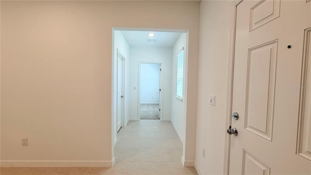 A tiled entryway leads to a hallway with a white door and a window — 5694 ENCHANTED MEADOW ALLEY UNIT A, CLERMONT, FL