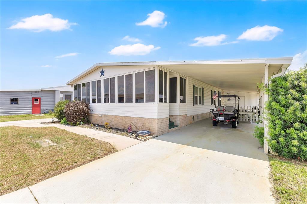 A single-story manufactured home features a screened-in porch, a carport, and a concrete driveway — 2527 LONGPINE LANE, ST CLOUD, FL