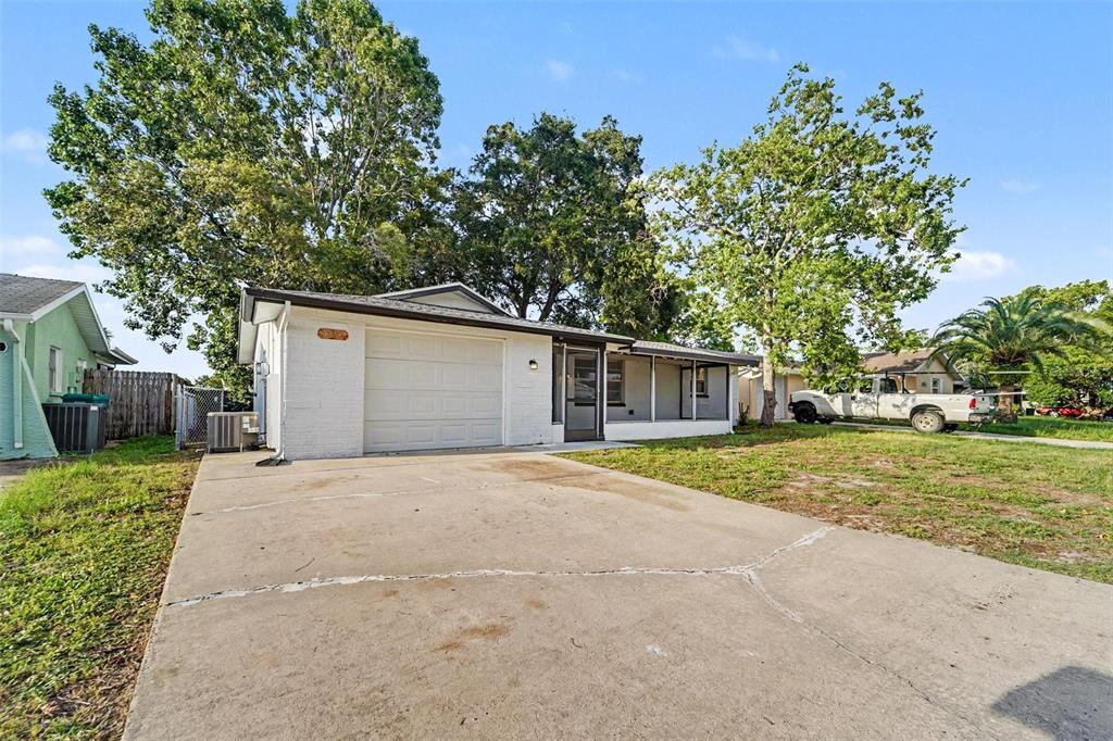 A white brick house with a garage and a screened front porch under large trees — 7207 SANDALWOOD DRIVE, PORT RICHEY, FL