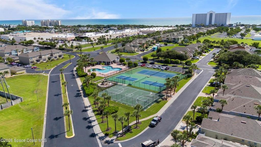 An aerial view shows a residential community with tennis courts, a swimming pool, and buildings — 3271 TITANIC CIRCLE UNIT 39, INDIALANTIC, FL