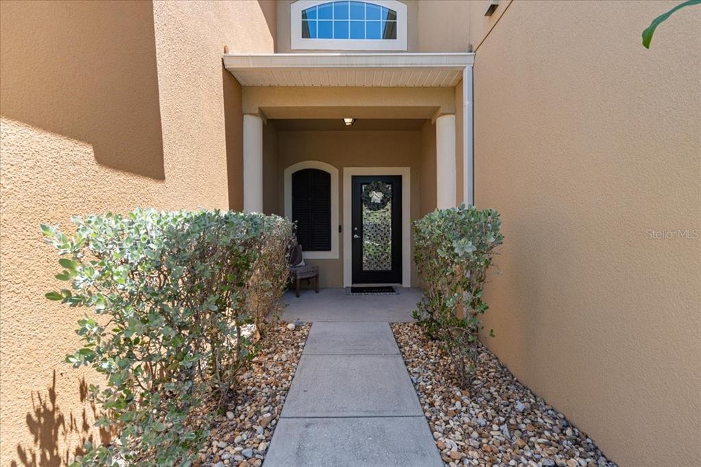 A concrete walkway leads to a covered entryway with a black front door and columns — 3271 TITANIC CIRCLE UNIT 39, INDIALANTIC, FL
