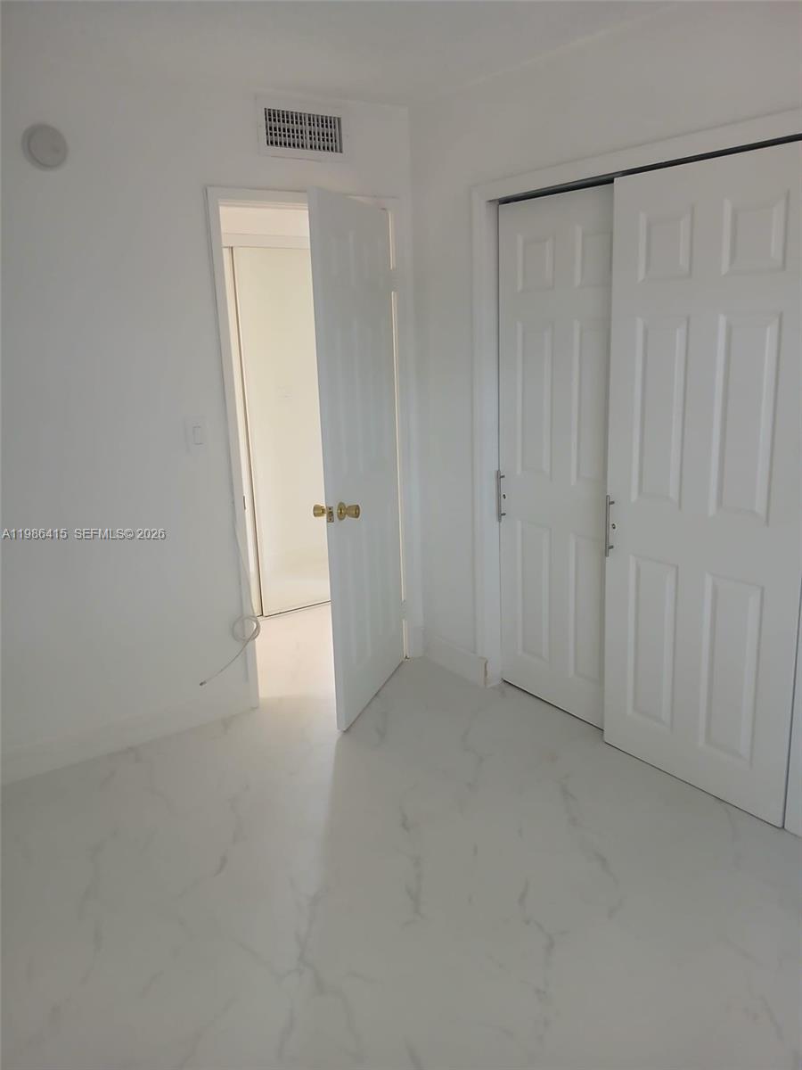 A room with white walls, white marble-look tile flooring, a closet, and an open doorway — 8405 NW 8th St # 311, Miami FL 33126, MIAMI, FL