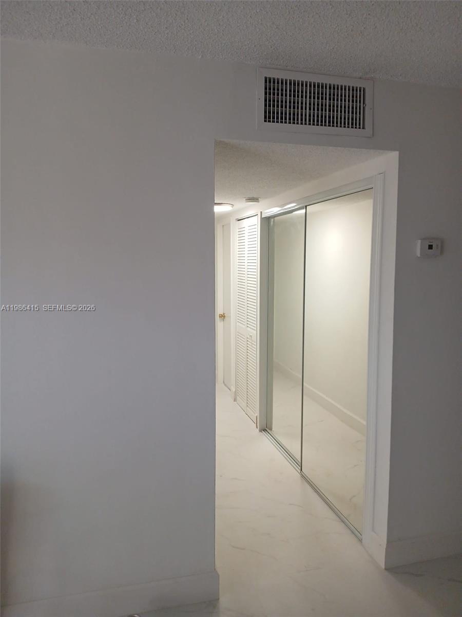 A hallway features white tile flooring, mirrored closet doors, and a louvered door — 8405 NW 8th St # 311, Miami FL 33126, MIAMI, FL