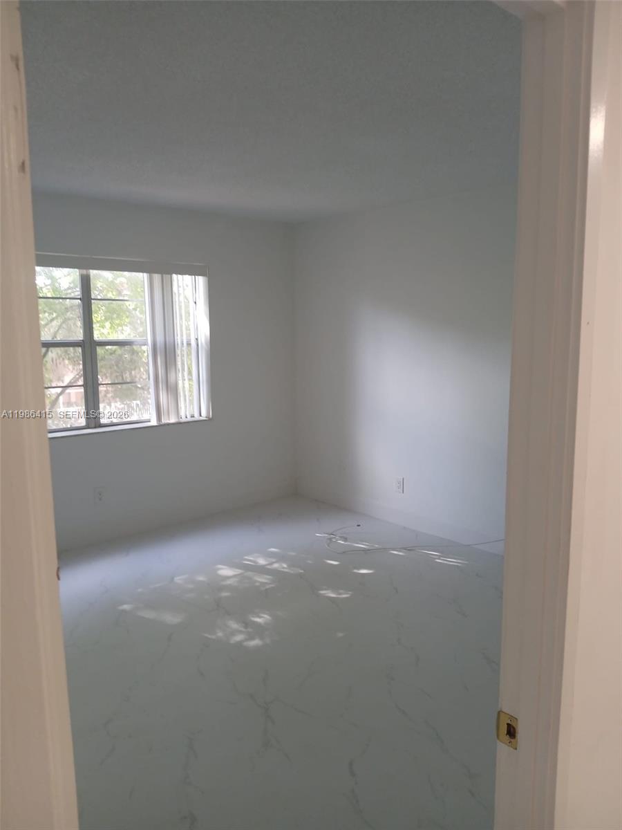 An empty bedroom features white walls, a window with vertical blinds, and white marble-patterned flooring — 8405 NW 8th St # 311, Miami FL 33126, MIAMI, FL