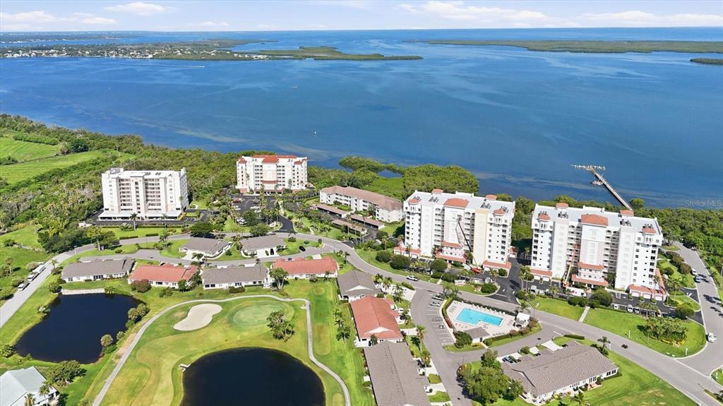 An aerial view shows a waterfront residential complex with multiple buildings, pools, and a golf course — 2725 TERRA CEIA BAY BOULEVARD UNIT 103, PALMETTO, FL
