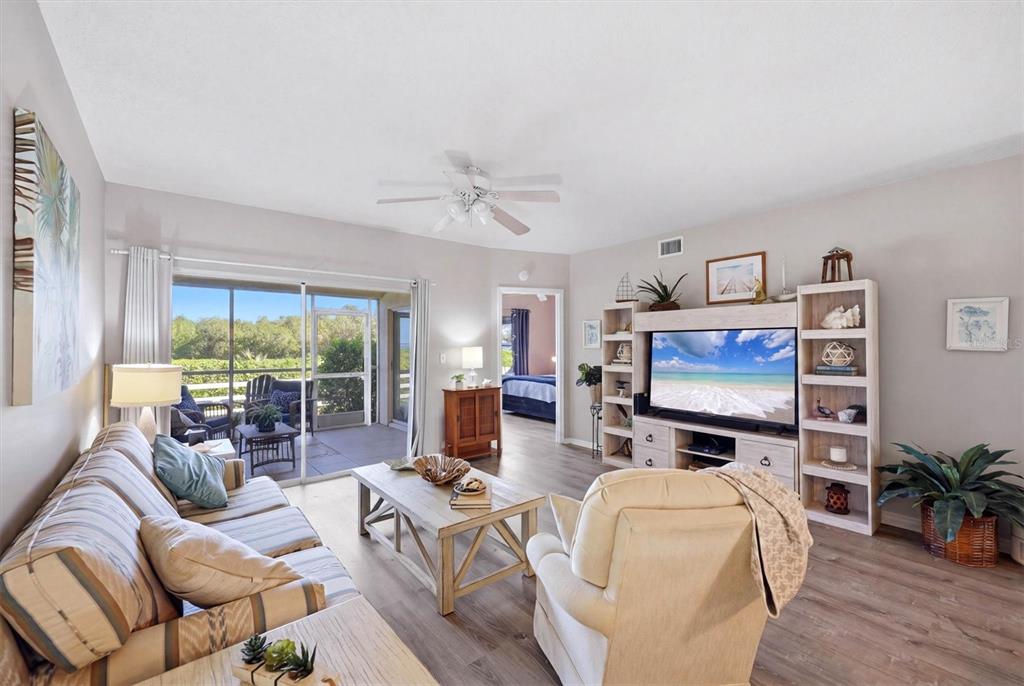 A living room with a sofa, armchair, coffee table, media console, and a screened-in patio — 2725 TERRA CEIA BAY BOULEVARD UNIT 103, PALMETTO, FL