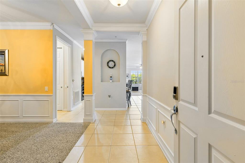 An entryway with tile flooring, wainscoting, and a decorative arched wall niche leads to a living area — 7903 SEMINOLE BOULEVARD UNIT 2208, SEMINOLE, FL
