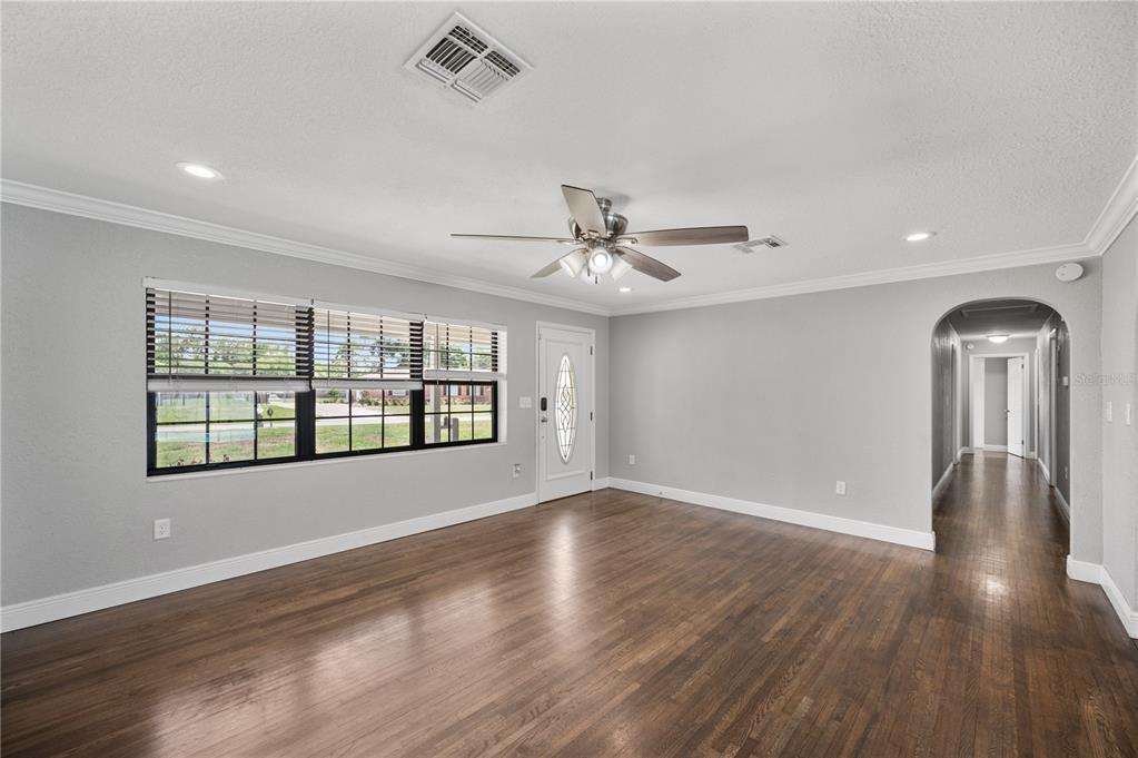 A living room with gray walls, dark wood floors, a ceiling fan, and a front door — 510 WINDERMERE DRIVE, LAKELAND, FL
