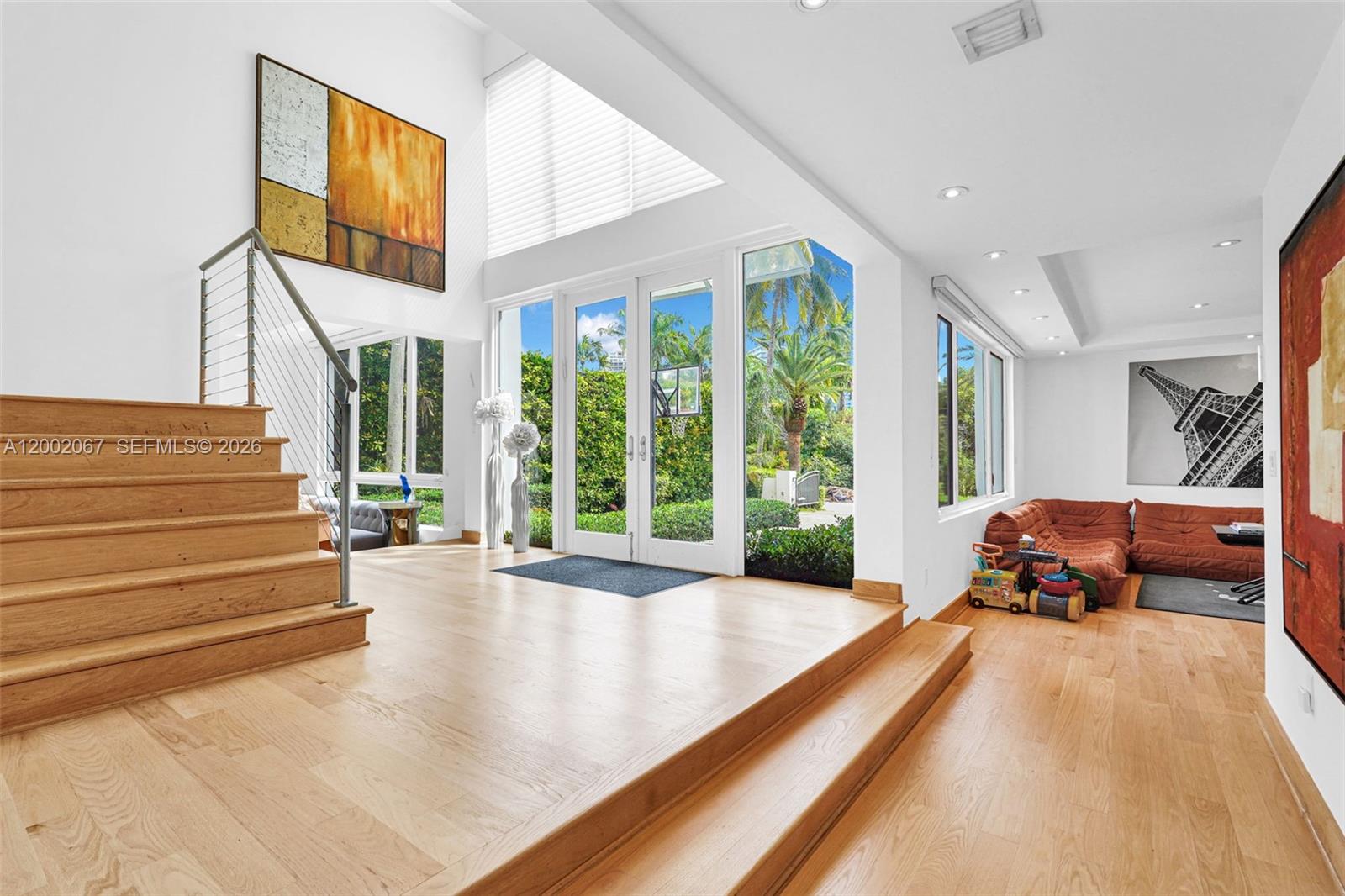 A living room features light wood floors, a sunken seating area, and a staircase — 145 Biscay Dr, Bal Harbour FL 33154, BAL HARBOUR, FL