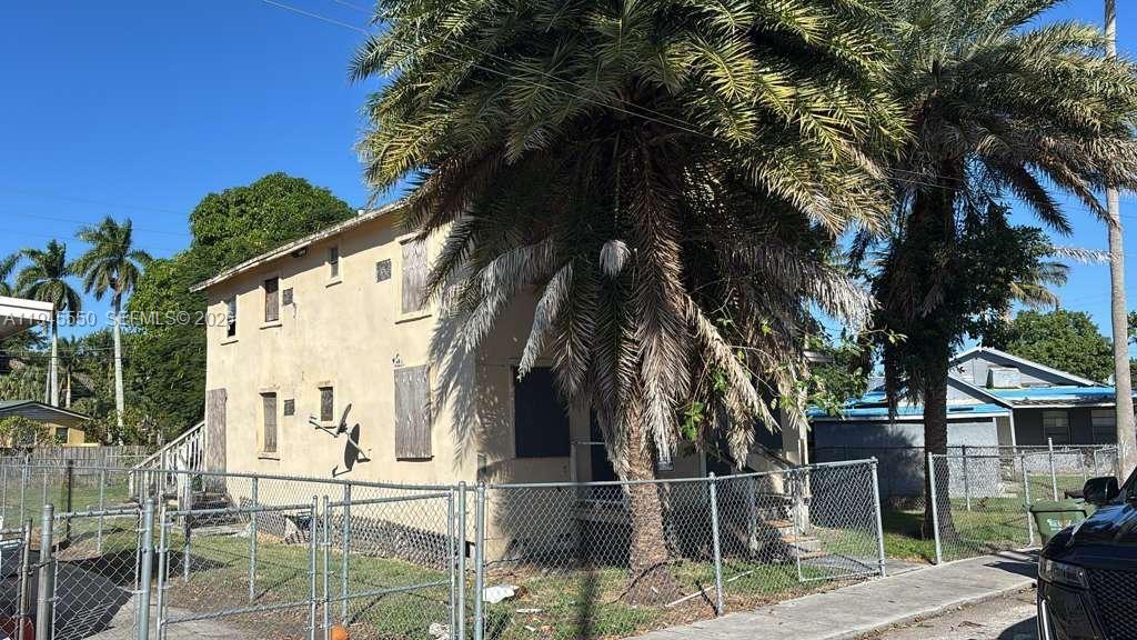 A two-story beige building with boarded-up windows stands behind a chain-link fence — 263 Carissa Dr, Pahokee FL 33476, PAHOKEE, FL