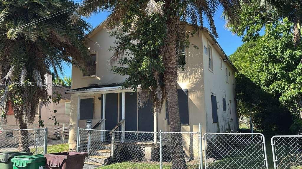 A two-story house with boarded-up windows and a front porch behind a chain-link fence — 263 Carissa Dr, Pahokee FL 33476, PAHOKEE, FL