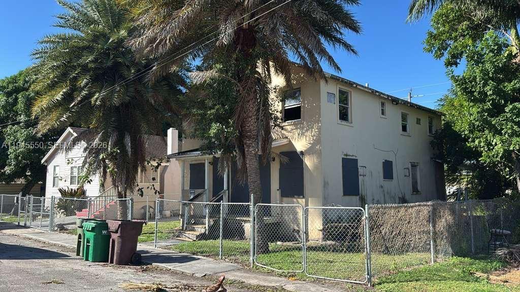 A two-story house with boarded-up windows and a chain-link fence in the front yard — 263 Carissa Dr, Pahokee FL 33476, PAHOKEE, FL