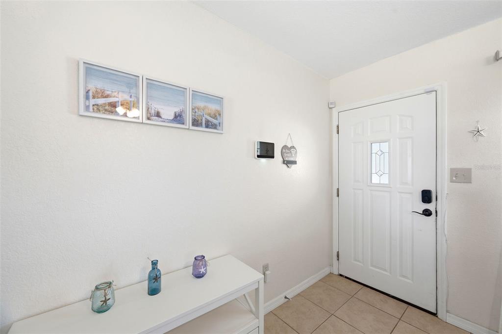An entryway features a white console table, wall art, and a white front door — 8685 MAGNOLIA DRIVE, SEMINOLE, FL
