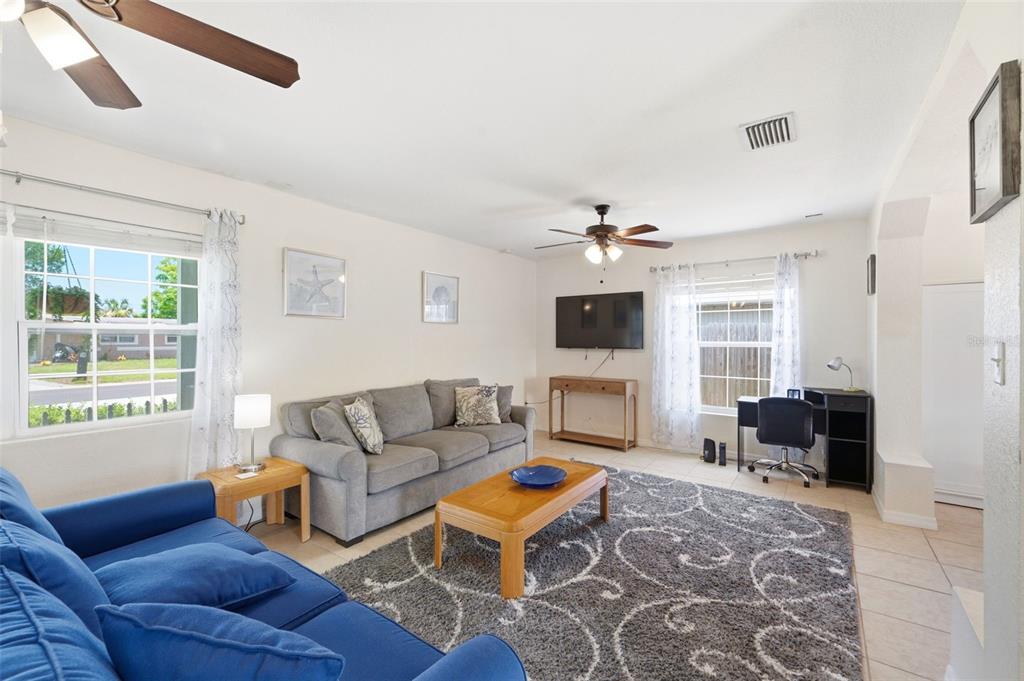 A living room features a blue sofa, a gray sofa, a coffee table, and a desk — 8685 MAGNOLIA DRIVE, SEMINOLE, FL